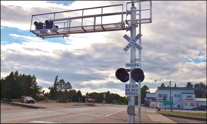 A metal railroad crossing gate with signs and lights